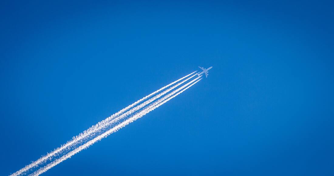 Avión atravesando el cielo azul, dejando una estela tras de sí. | Cómo superar con éxito tu primer viaje en avión | Glutenacious Life.com